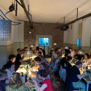 Viele menschen sitzen an zwei langen Tischen zusammen beim Dinner von Nomade